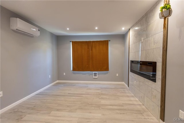 empty room featuring a wall unit AC and light hardwood / wood-style flooring