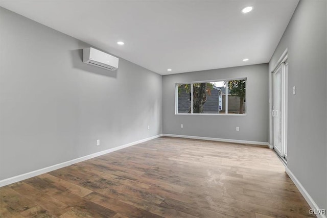 empty room featuring wood-type flooring and a wall mounted air conditioner