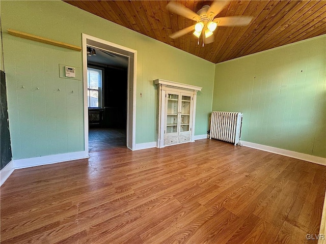 empty room with hardwood / wood-style floors, ceiling fan, wood ceiling, and radiator