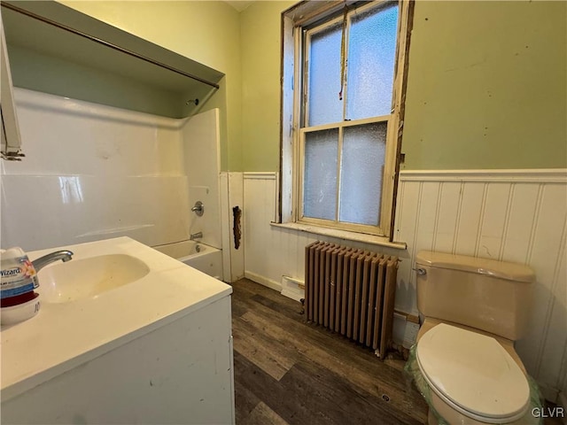 full bathroom with radiator heating unit, shower / bath combination, toilet, hardwood / wood-style flooring, and sink