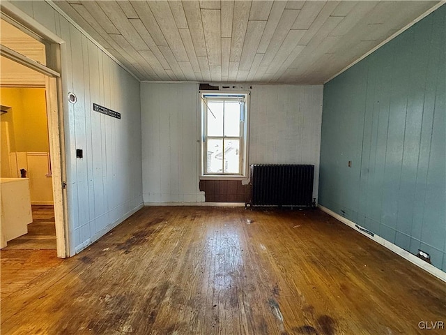 unfurnished room featuring radiator heating unit, wood walls, hardwood / wood-style flooring, and wood ceiling