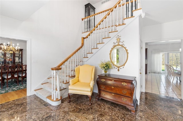 staircase featuring hardwood / wood-style floors, a high ceiling, and a chandelier