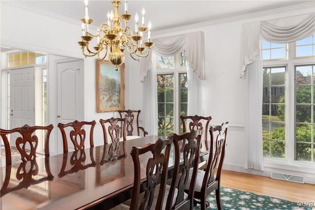 dining space with ornamental molding, light wood-type flooring, a healthy amount of sunlight, and a chandelier