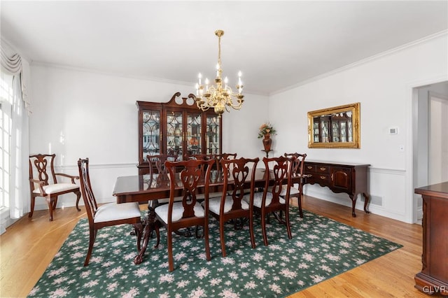 dining space featuring light hardwood / wood-style floors, a chandelier, and ornamental molding