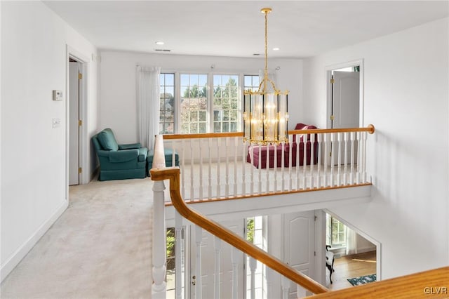 stairs with a notable chandelier and carpet floors