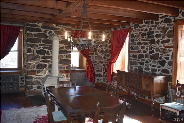 dining space featuring beam ceiling, radiator heating unit, a wood stove, and dark hardwood / wood-style flooring