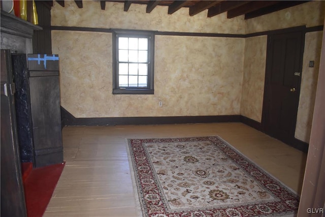 empty room featuring beamed ceiling and hardwood / wood-style floors