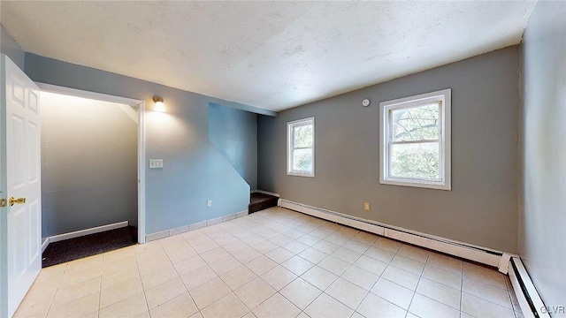 unfurnished room with light tile patterned floors and a baseboard radiator