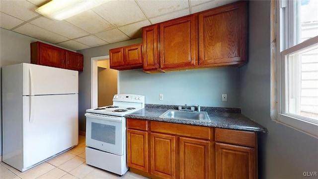 kitchen with sink, white appliances, a drop ceiling, and light tile patterned flooring