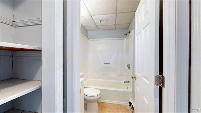 bathroom with a drop ceiling, tile patterned flooring, toilet, and shower / bathtub combination