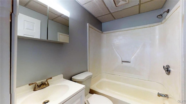 full bathroom featuring toilet, vanity, a drop ceiling, and shower / bathtub combination