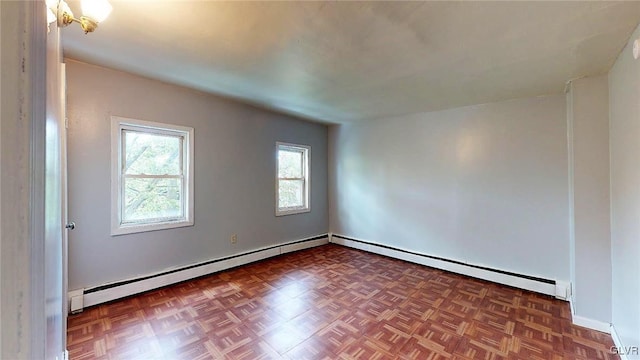 spare room featuring dark parquet flooring and a baseboard heating unit