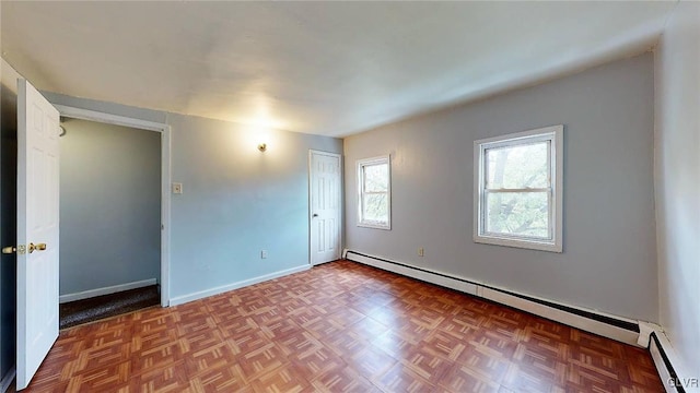 empty room featuring baseboard heating and parquet flooring