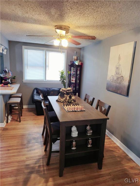 dining area featuring hardwood / wood-style floors, ceiling fan, and a textured ceiling