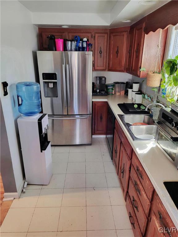 kitchen with black dishwasher, light tile patterned floors, sink, and stainless steel fridge