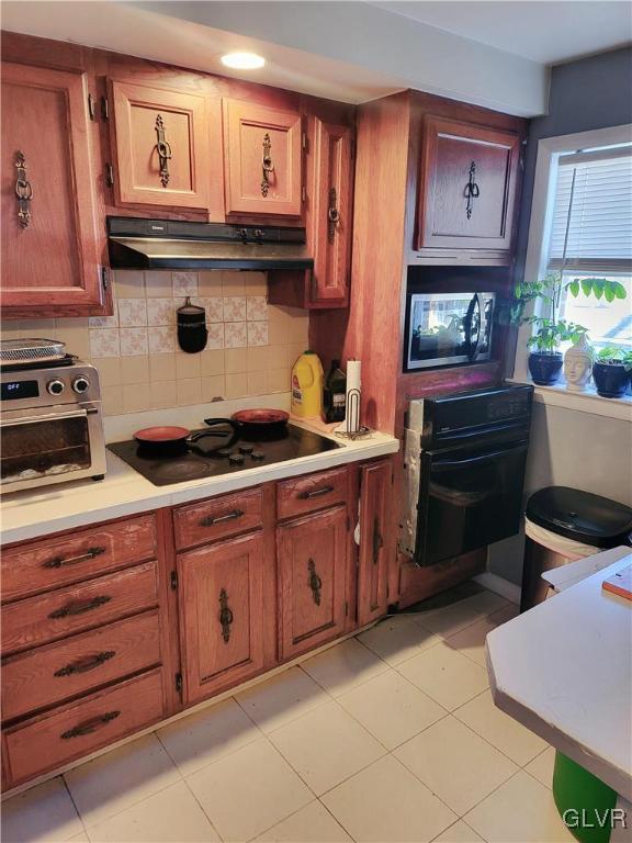 kitchen featuring black electric stovetop, light tile patterned floors, and backsplash