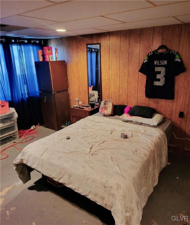 bedroom featuring fridge, wooden walls, and a drop ceiling