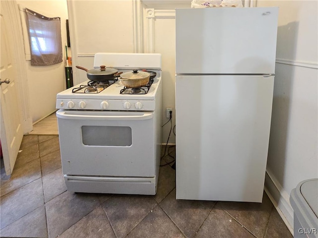 kitchen with white appliances and dark tile patterned flooring