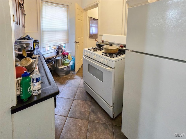 kitchen with dark tile patterned floors and white appliances