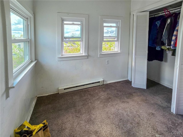 unfurnished bedroom featuring multiple windows, a closet, a baseboard heating unit, and dark carpet