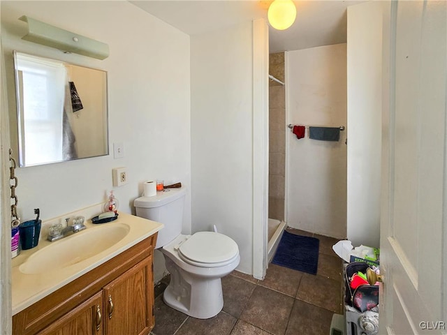 bathroom featuring tile patterned flooring, tiled shower, toilet, and vanity