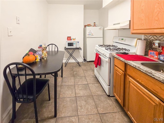 kitchen with ventilation hood, white appliances, sink, and light tile patterned floors