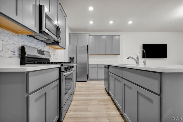 kitchen featuring sink, stainless steel appliances, gray cabinets, and light hardwood / wood-style flooring