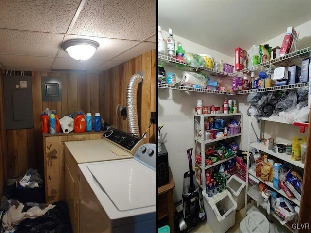 clothes washing area featuring electric panel, wooden walls, and washer and clothes dryer