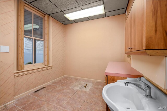 bathroom with a drop ceiling, sink, and tile patterned floors