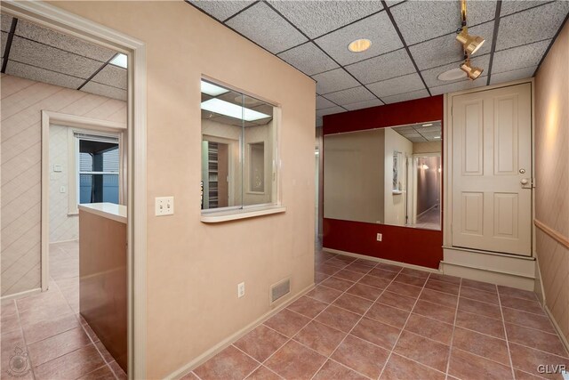 corridor with a drop ceiling and tile patterned flooring