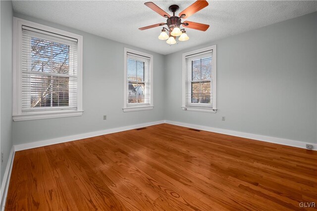 empty room with a textured ceiling, ceiling fan, and wood-type flooring