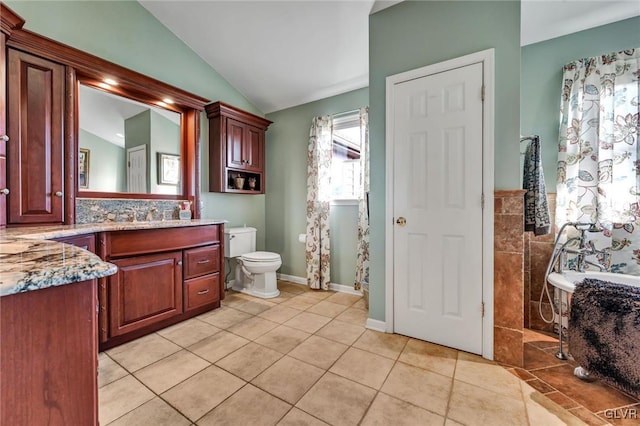 bathroom featuring a tub, vanity, lofted ceiling, tile patterned floors, and toilet