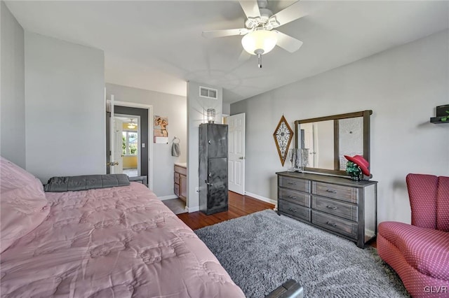 bedroom with dark wood-type flooring, ceiling fan, and ensuite bath