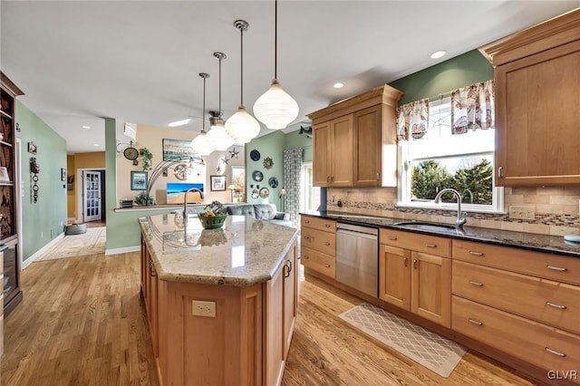 kitchen featuring light hardwood / wood-style floors, sink, hanging light fixtures, a kitchen island, and dishwasher