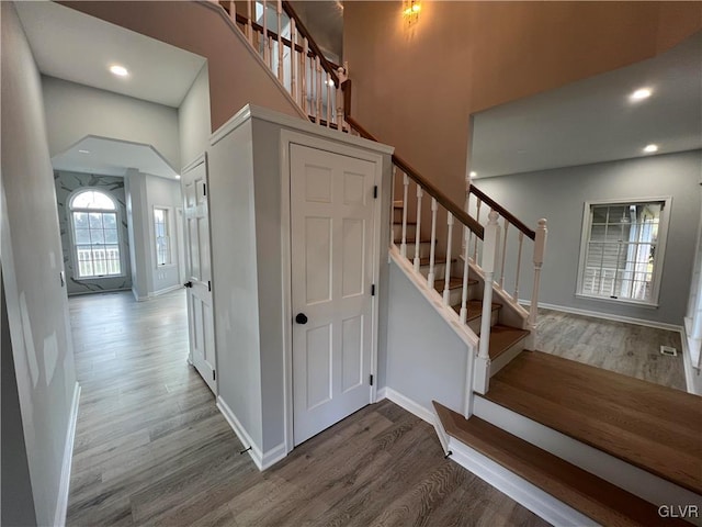 stairs with hardwood / wood-style floors and a high ceiling