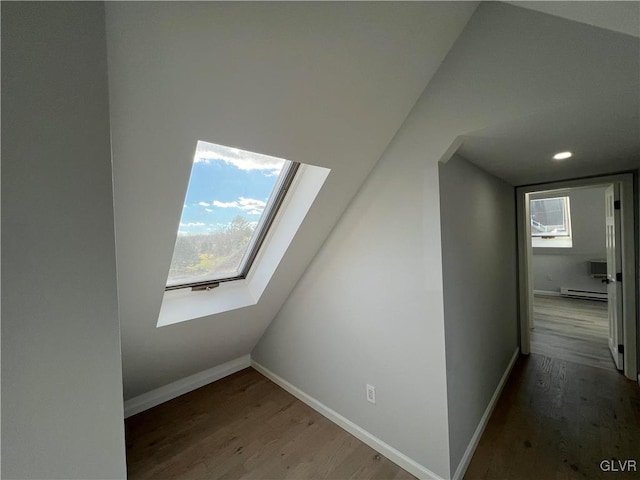 bonus room with hardwood / wood-style floors, vaulted ceiling with skylight, and a baseboard heating unit