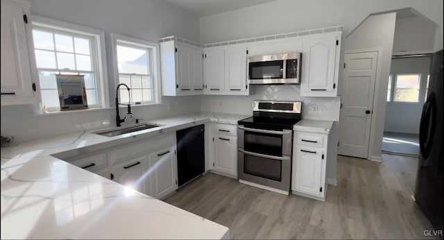 kitchen featuring light hardwood / wood-style floors, white cabinets, decorative backsplash, sink, and appliances with stainless steel finishes