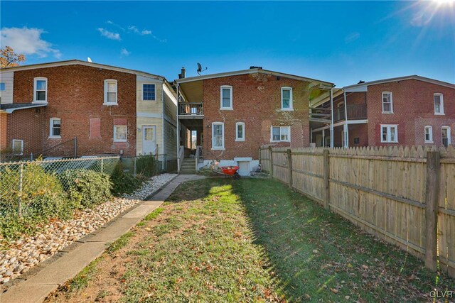 rear view of property featuring a lawn and a balcony