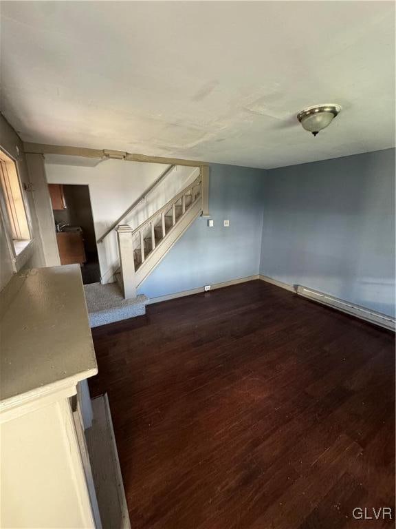 unfurnished living room with dark wood-type flooring and a baseboard radiator