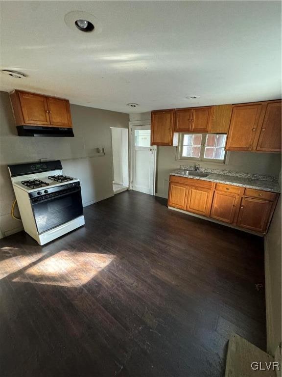 kitchen with dark wood-type flooring, sink, and gas range gas stove