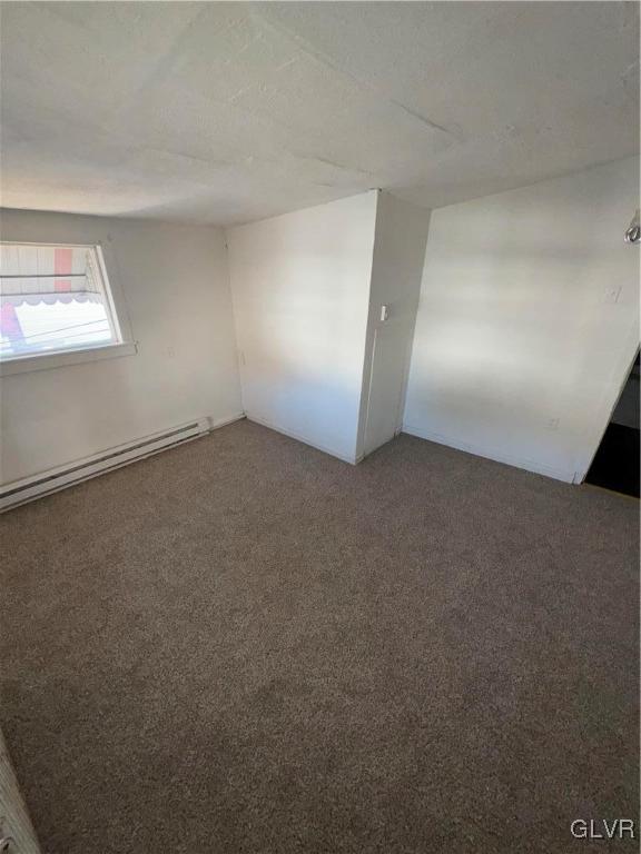 unfurnished room featuring a baseboard heating unit and carpet