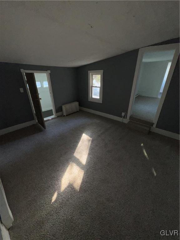 spare room with radiator heating unit, vaulted ceiling, and carpet floors