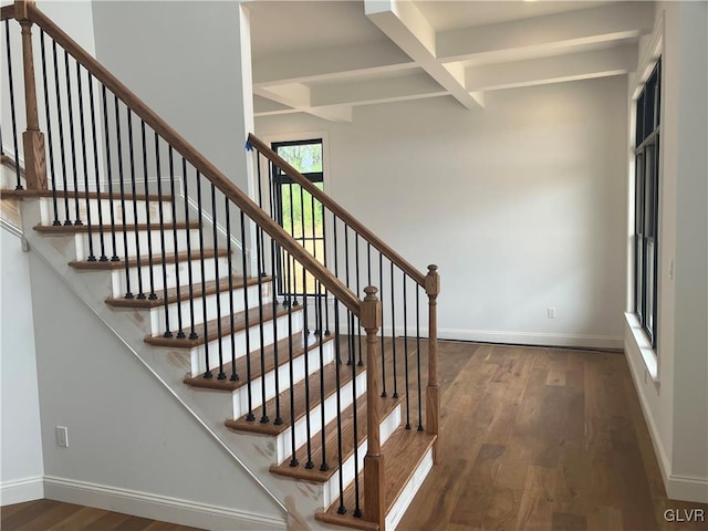 stairs featuring beamed ceiling, coffered ceiling, and wood-type flooring