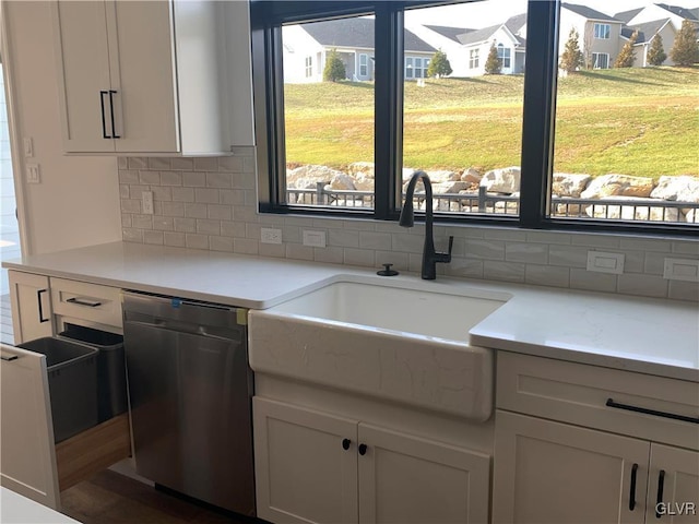 kitchen with white cabinets, tasteful backsplash, stainless steel dishwasher, and sink