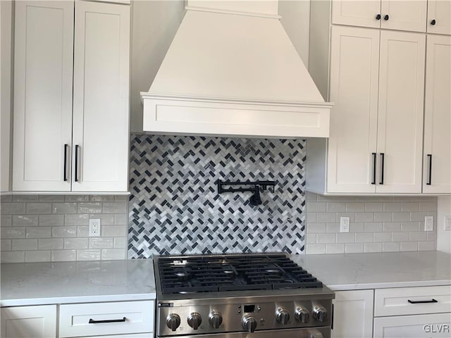 kitchen with stainless steel stove, white cabinets, and tasteful backsplash