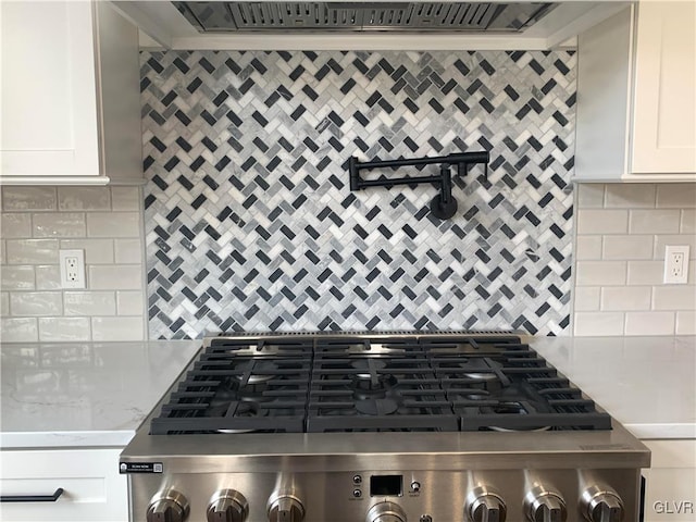 kitchen with white cabinetry, decorative backsplash, stainless steel range, and light stone counters