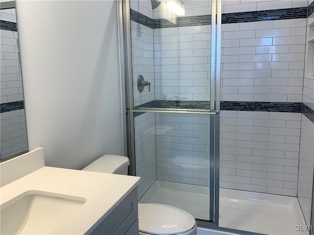 bathroom featuring toilet, vanity, and walk in shower