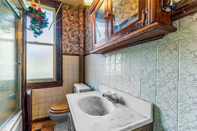 full bathroom featuring vanity, toilet, tile walls, and bath / shower combo with glass door