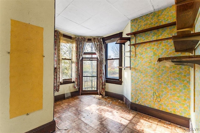 824 Wolf Ave, Easton, PA 18042 - unfurnished room with baseboards, healthy amount of natural light, wallpapered walls, and a drop ceiling