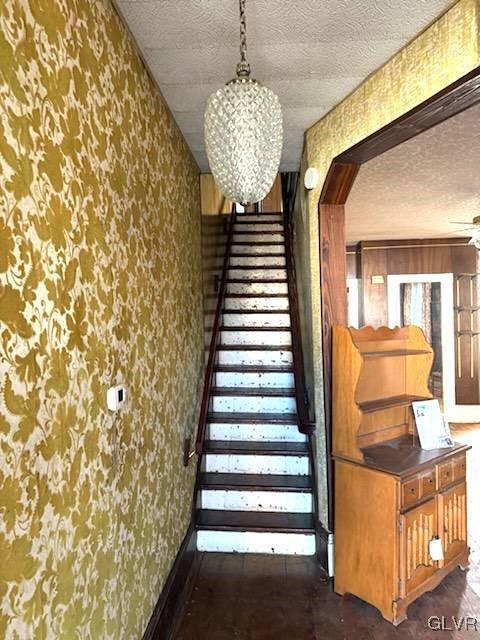 824 Wolf Ave, Easton, PA 18042 - staircase featuring wallpapered walls, a textured ceiling, arched walkways, and baseboards